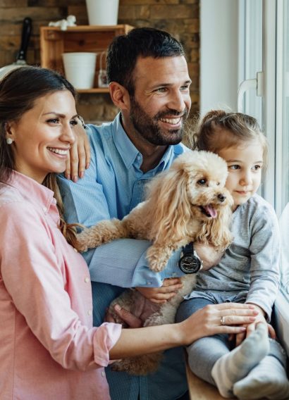 young-happy-family-and-their-dg-relaxing-by-the-windodw-at-home-and-looking-through-it